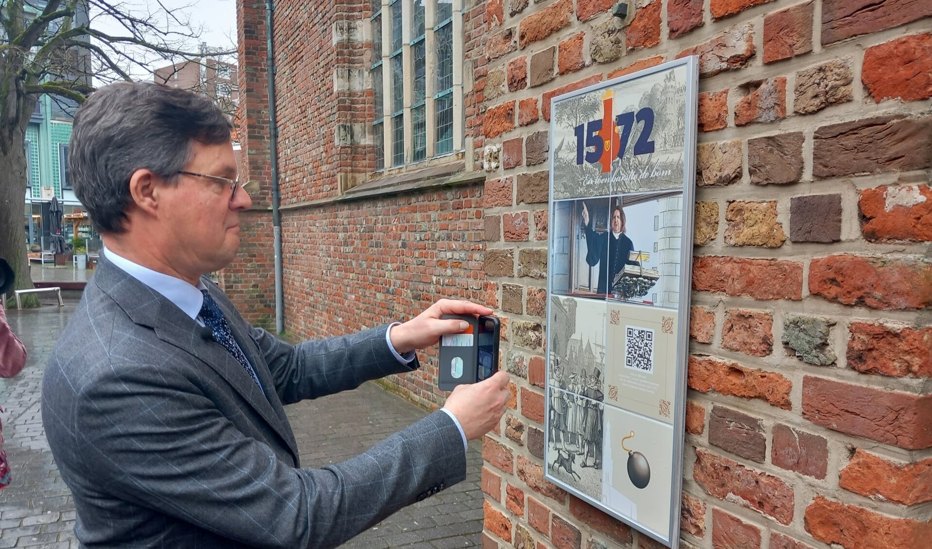 Burgemeester Bas van den Tillaar neemt met het scannen van de QR-code het hoorspel in gebruik.