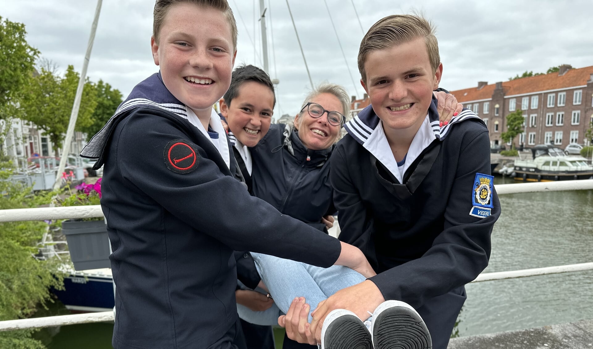 De Middelburgse havenmeester Susanne Maes wordt op handen gedragen door drie leden van Zeekadetkorps Veere
