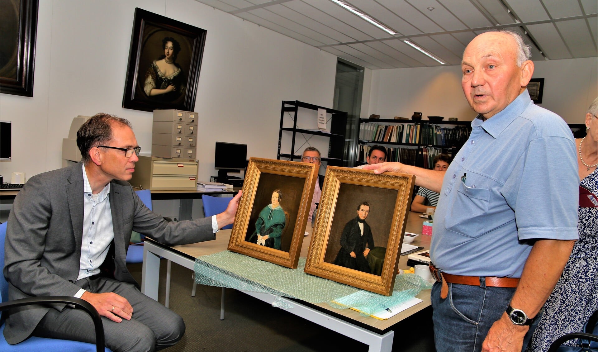 Doeleman overhandigt de portretten aan wethouder Hoek.
