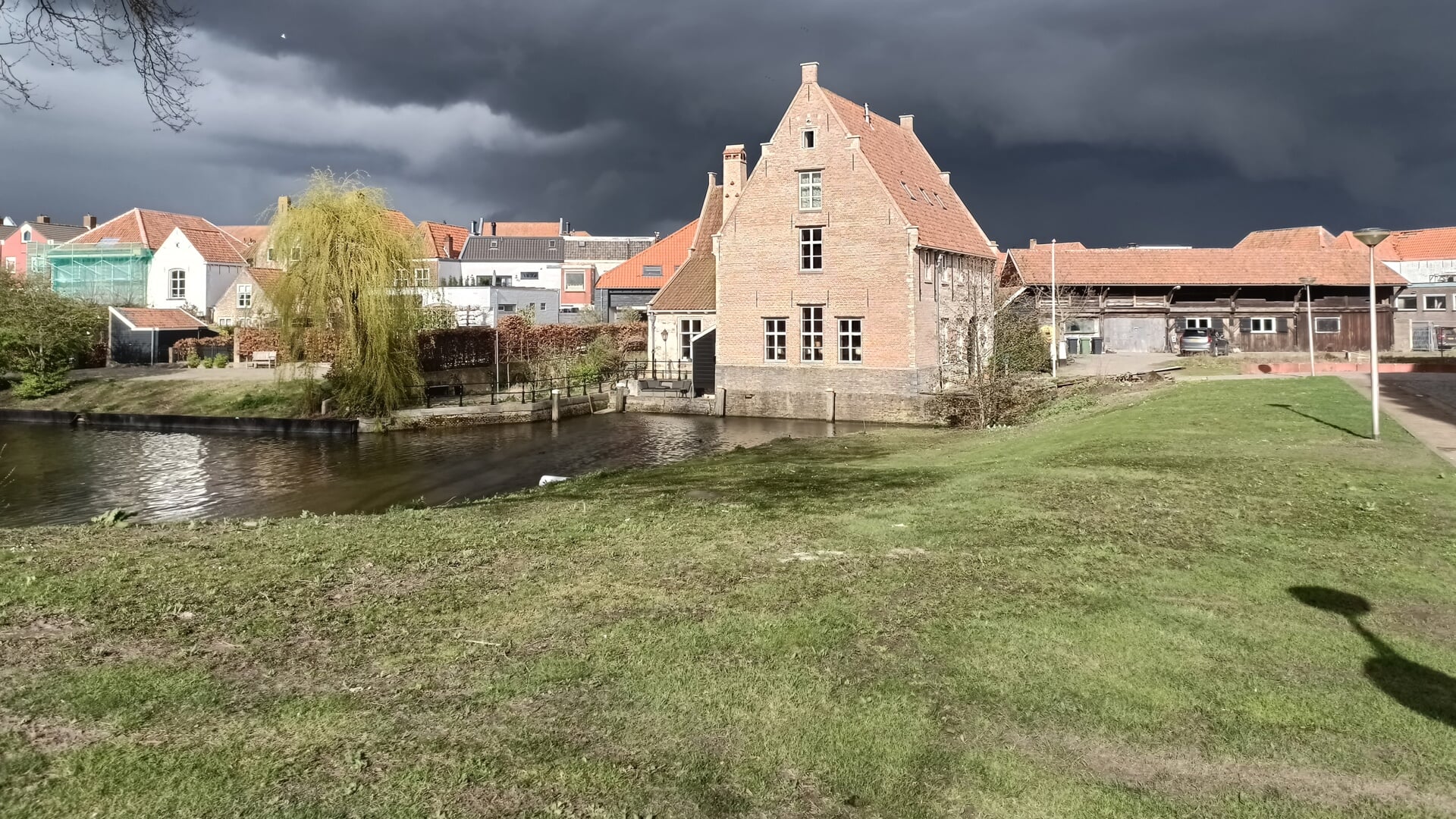 Donkere wolken pakken zich samen boven Bergen op Zoom. De oude watermolen aan het Molenpad en de Vissershaven baadt echter nog volop in de zon.