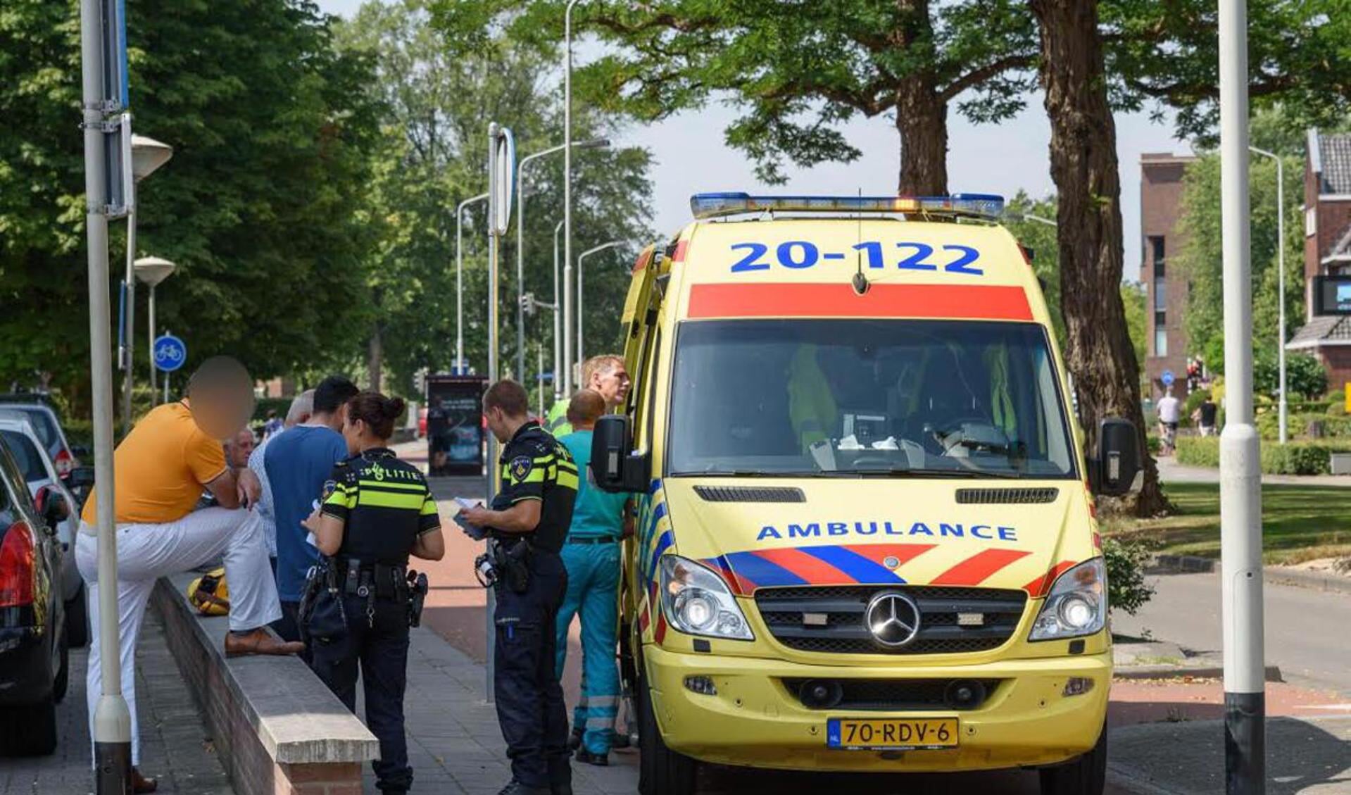 De ambulance zal de gewonde fietsster neer het ziekenhuis vervoeren.