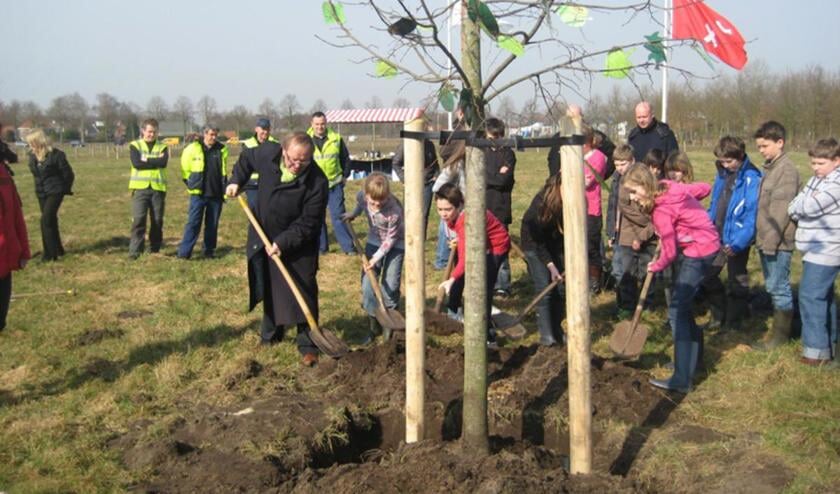 Wethouder Janus Oomen schept samen met leerlingen van basisschool de Rosmolen zand bij de net geplante Linde.