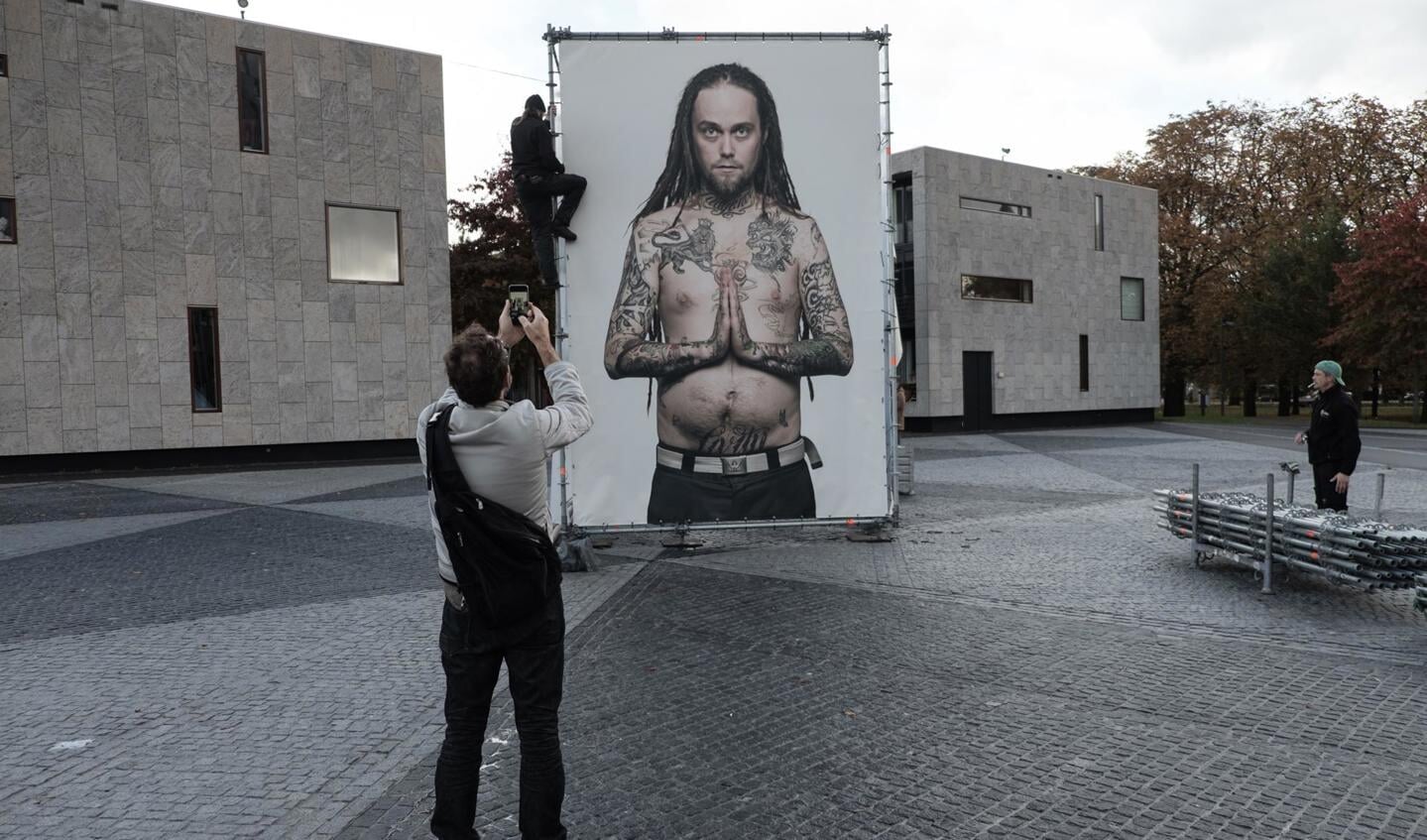 Medewerkers van BredaPhoto ontmantelen de tattoo-serie van fotograaf Ralf Mitsch. De maker zelf kijkt toe.
