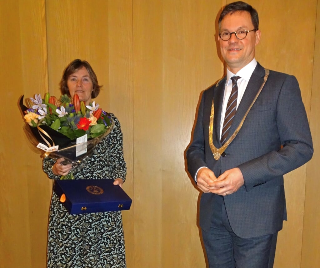 Marleen Poortvliet krijgt het lintje en bloemen van burgemeester Bas van den Tillaar.