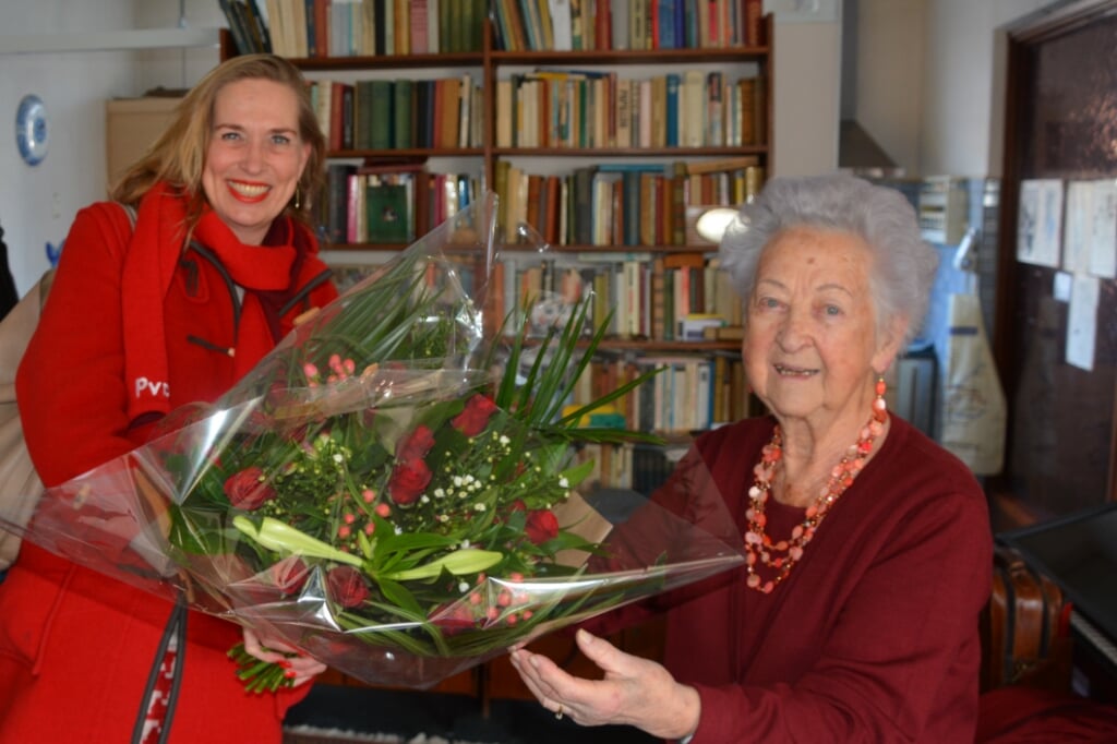 Jubilaris Sophia Mensen krijgt rode rozen van Barbara Oomen.