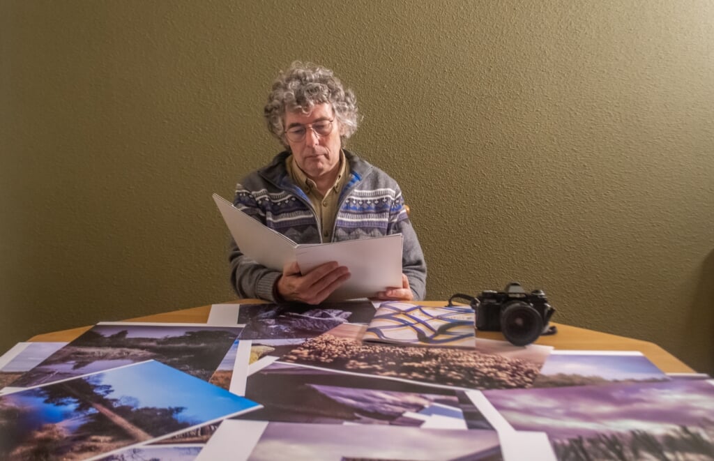 Rob den Braasem aan tafel met zijn foto's en zijn boek.