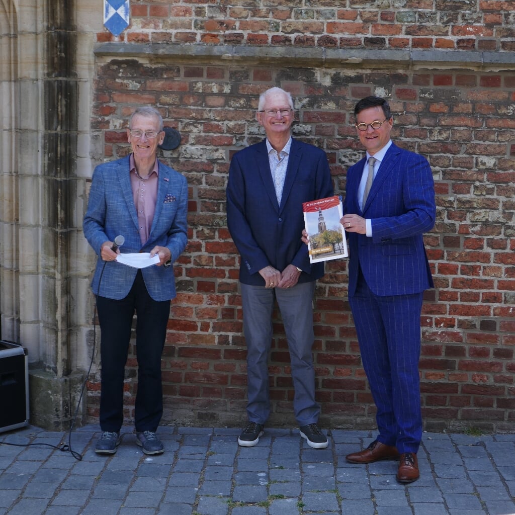 Burgemeester Van den Tillaar krijgt het eerste exemplaar van de brochure overhandigd.