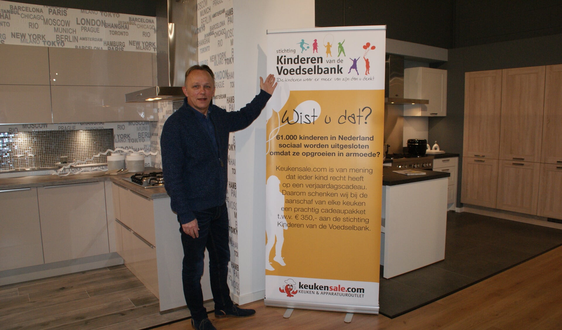 Eigenaar Aad de Beus van Keukensale toont de banner van Kinderen van de Voedselbank.