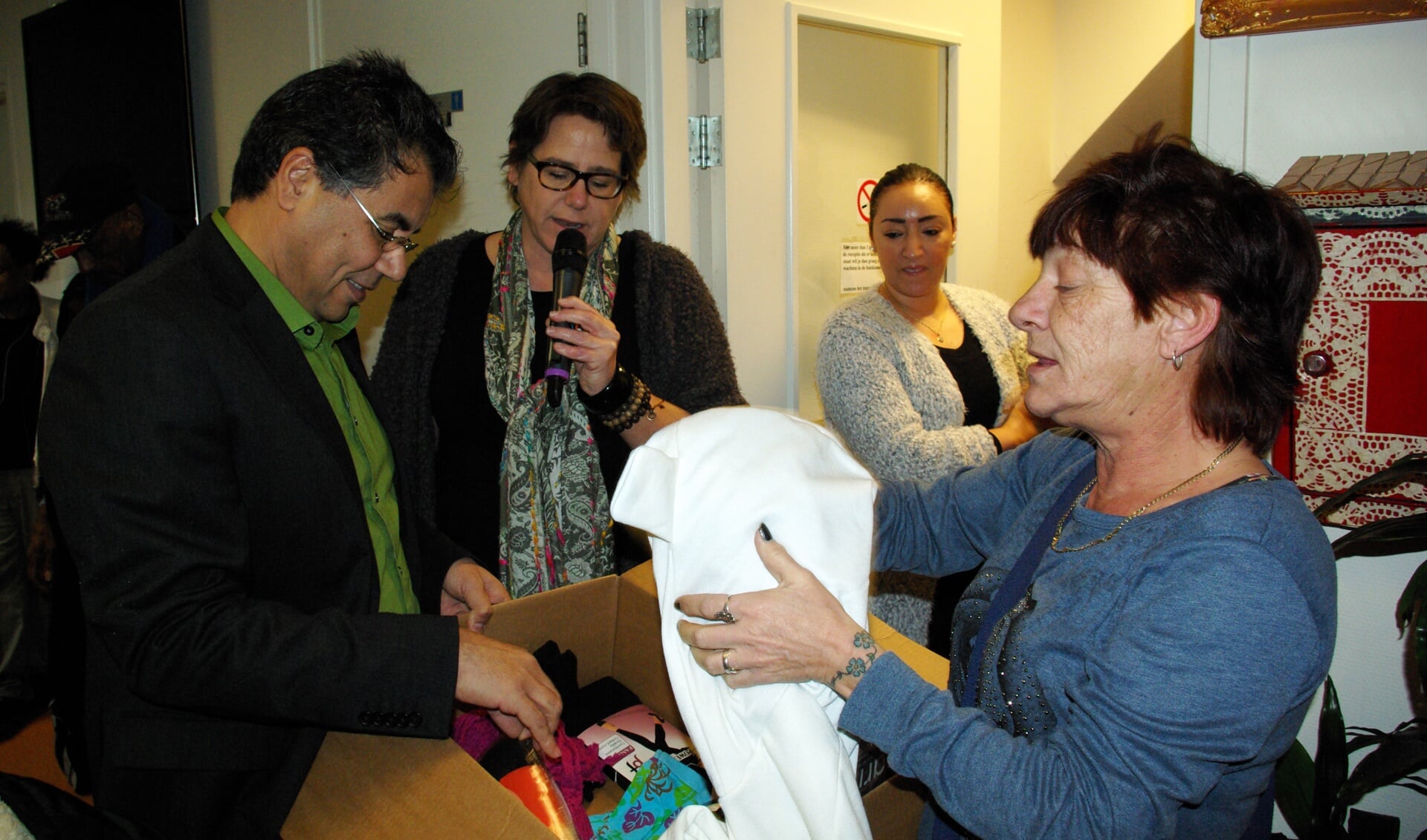 Mustapha Boufassil, Barbara Berkelaar en een cliënten van PerspeKtief bekijken de inhoud van het kledingpakket. 