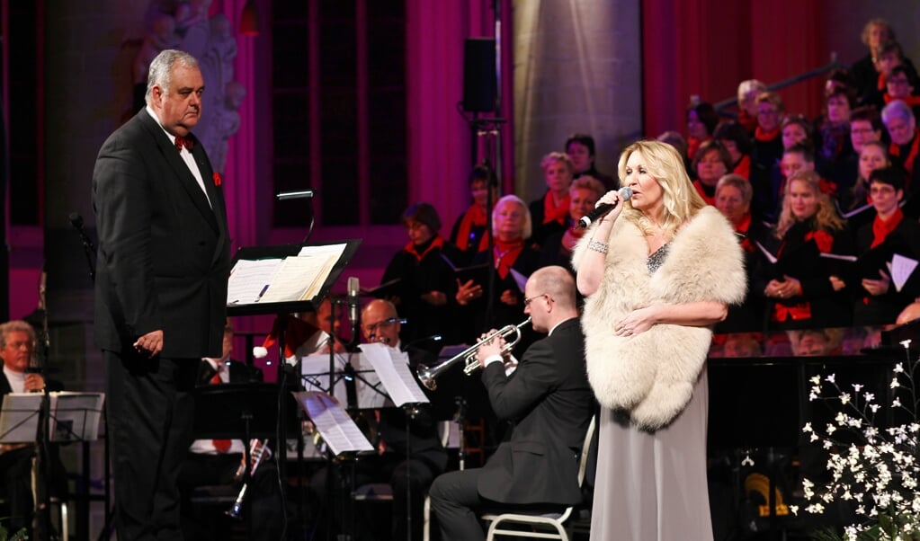 Dirigent Gerard Breäs, die ook komende editie de muzikale leiding op zich heeft genomen, ziet hoe Petra Berger (rechts) het publiek verblijdt met mooie kerstliederen.  