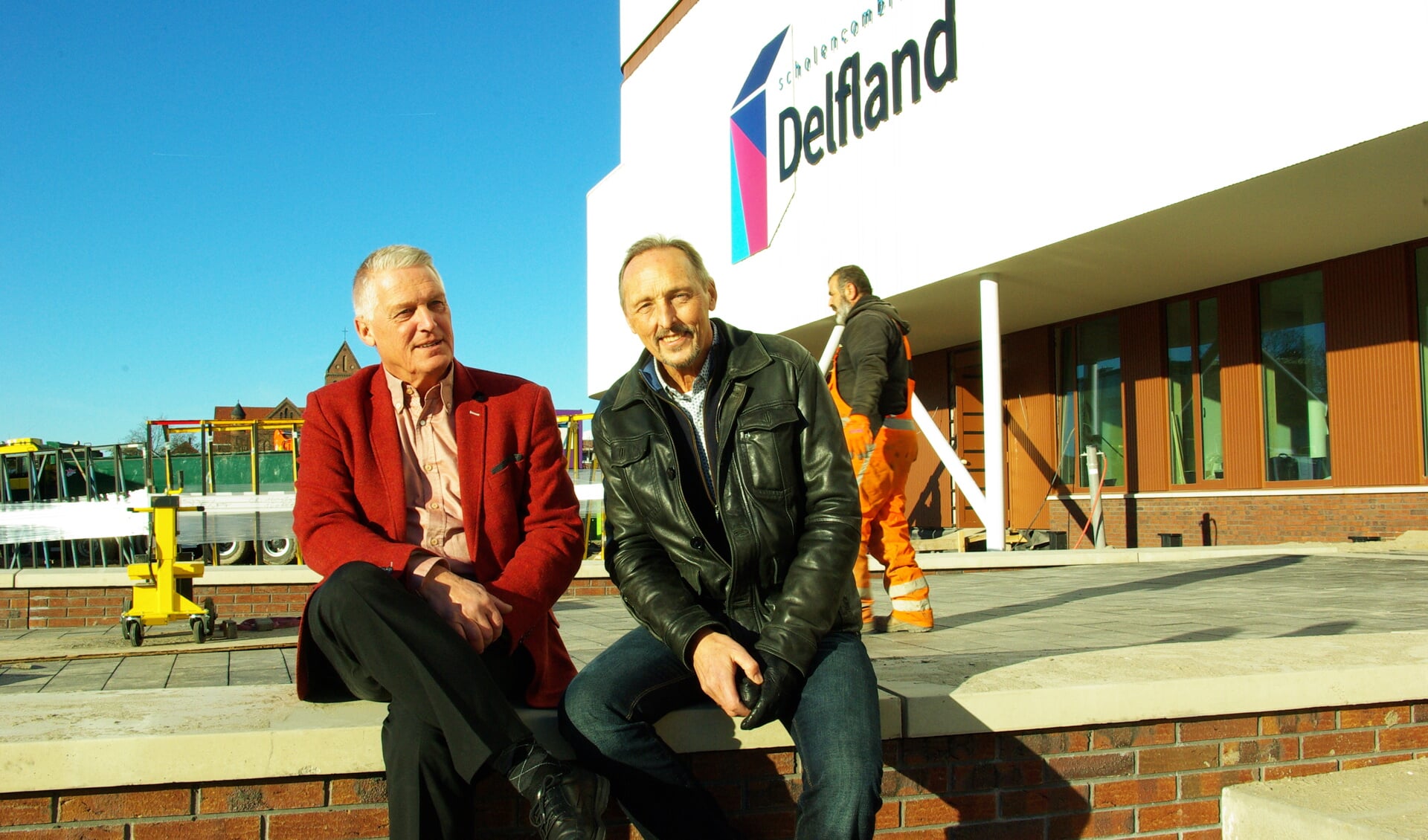 Charles Barto (links) en Herman de Vries, met achter hen het nieuwe schoolgebouw van SC Delfland. 