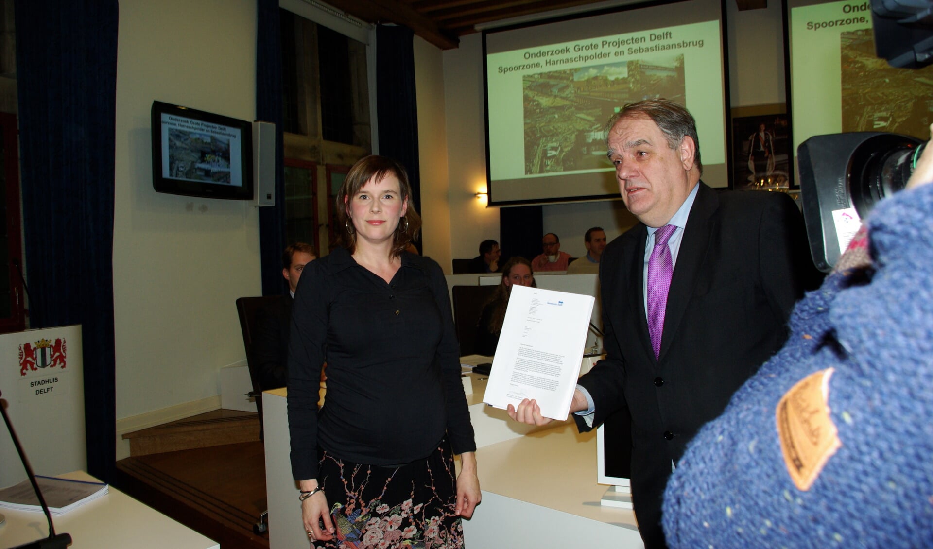 Burgemeester Bas Verkerk (rechts) ontving het eerste exemplaar van het onderzoek naar de financiële malaise waarin Delft verzeild is geraakt. Links Lieke van Rossum, voorzitter van de onderzoekscommissie. 