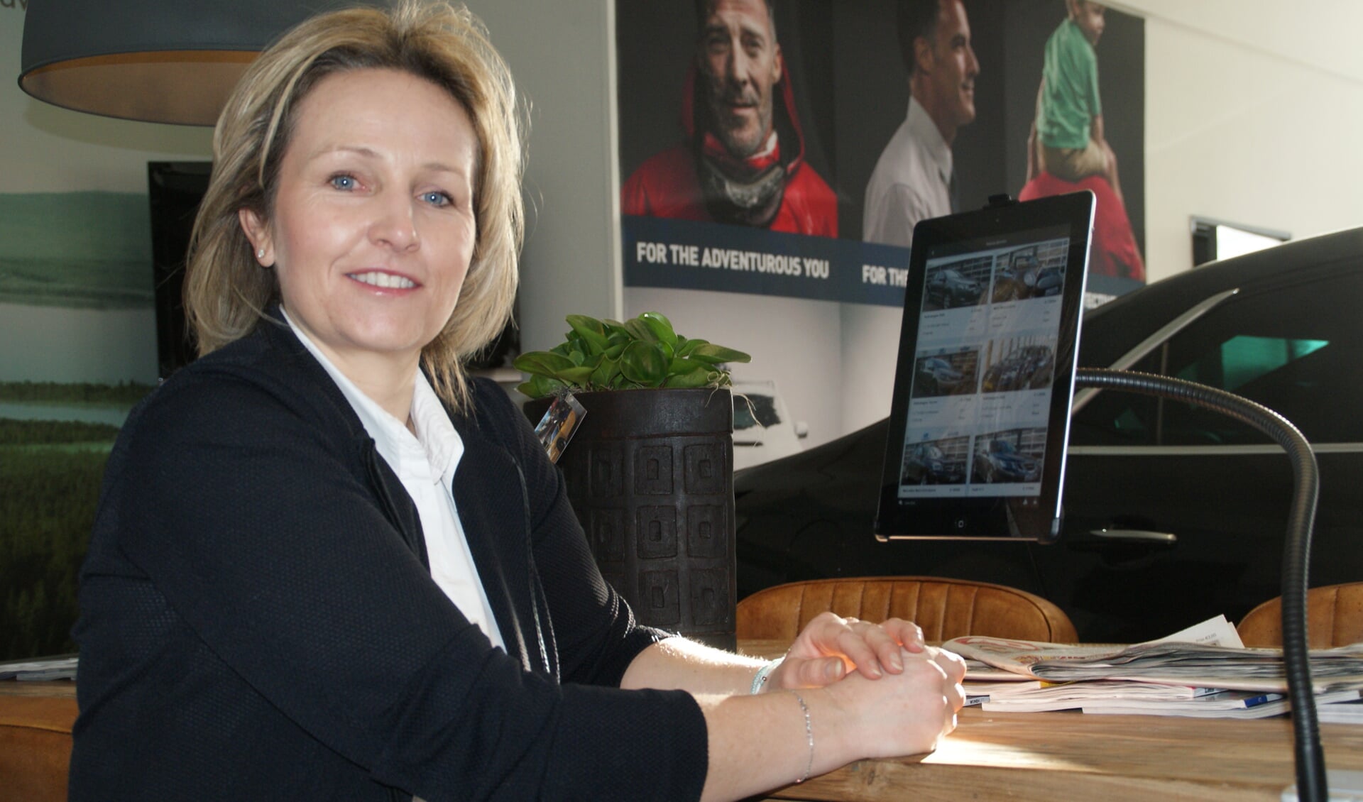Receptioniste Anja de Wit, even achter de balie vandaan, aan de leestafel bij de tablet met Harteveld-app.