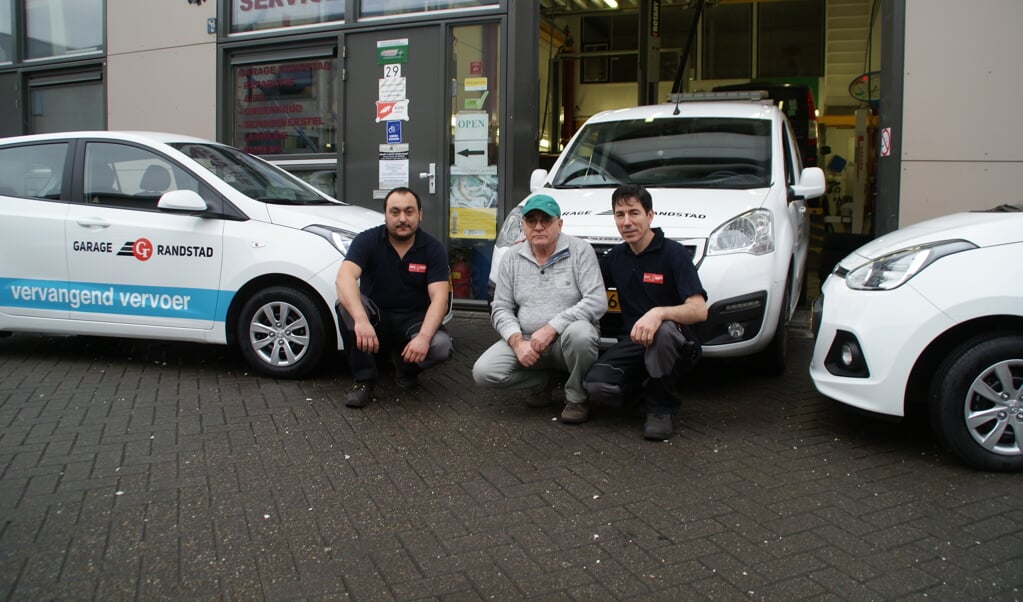 Het team van Garage Randstad bij de nieuwe voertuigen, met in het midden de eigenaar.