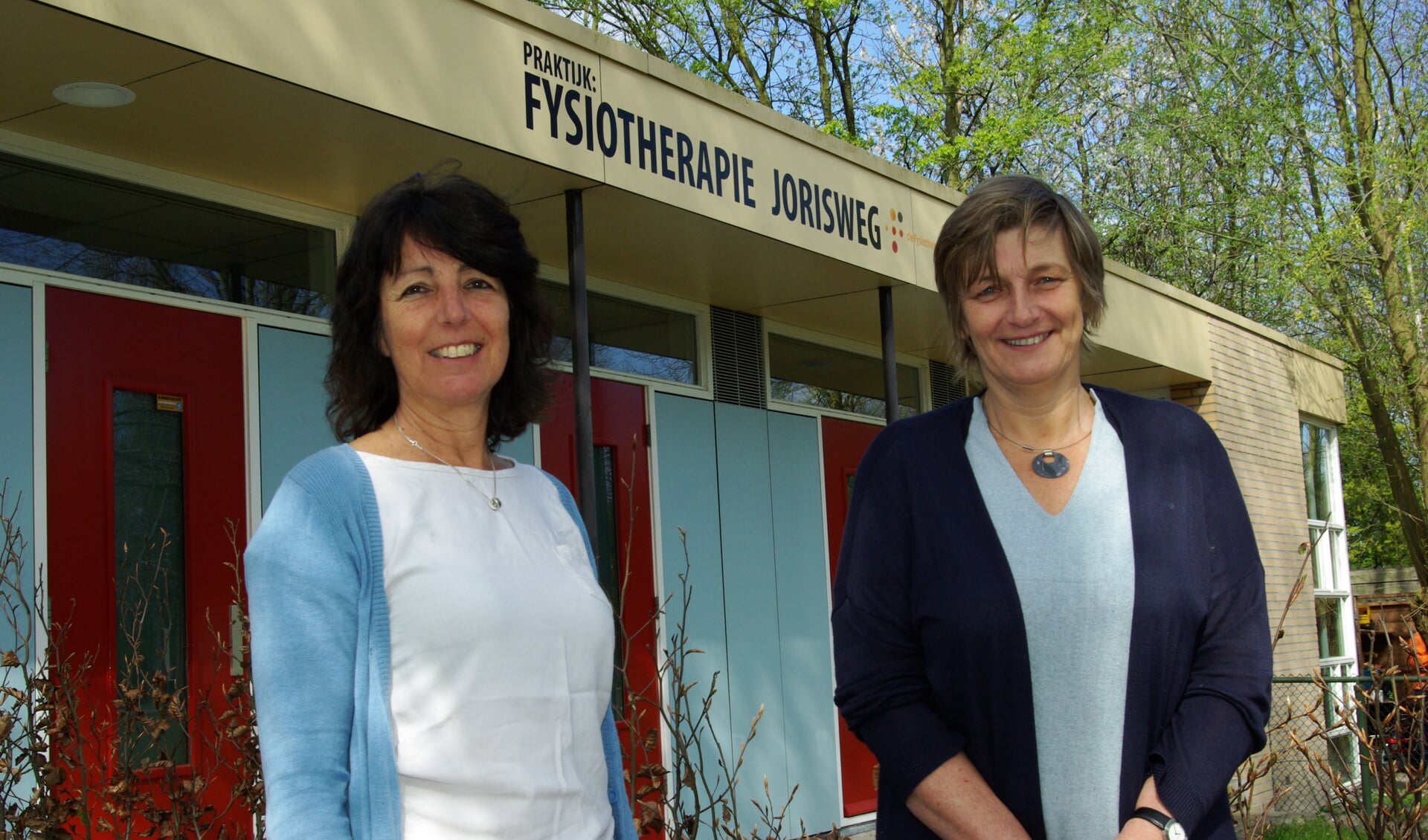 Marianne Kouwenhoven en Anneloes de Zeeuw van Fysiotherapie Jorisweg, met achter hen de nieuwe gevelreclame. 