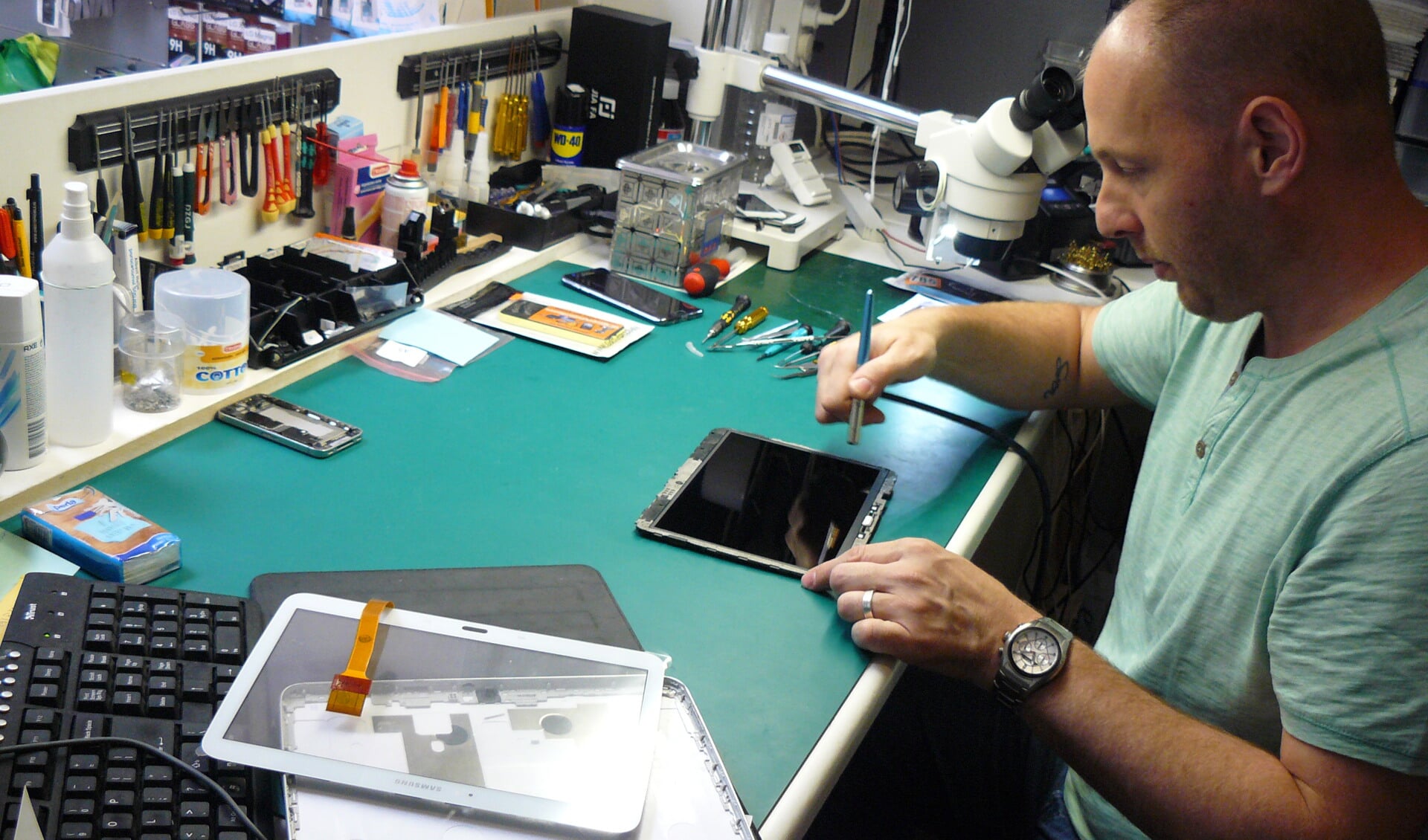 Marco repareert een tablet met een beschadigd scherm. 