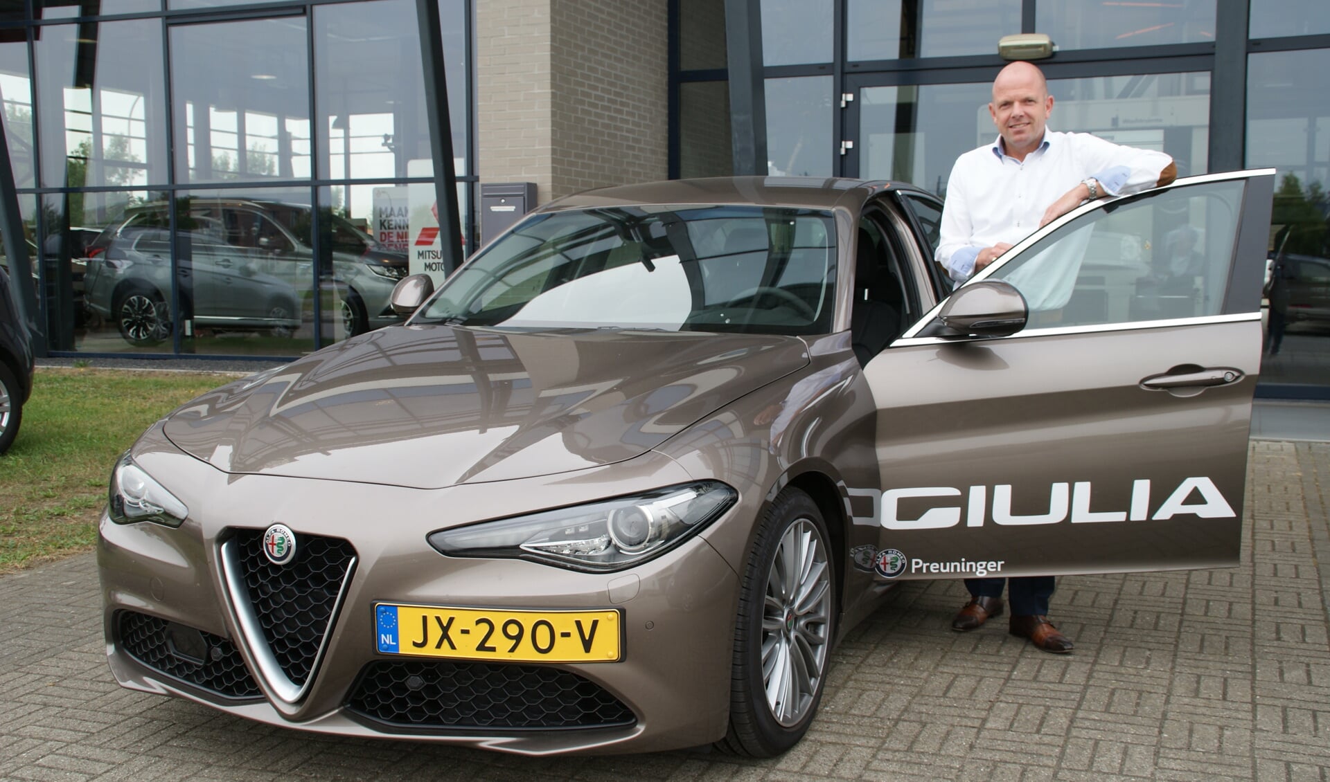 Robert den Toom van Alfa Romeo bij de nieuwe Giulia voor de hoofdingang van Preuninger Haagland.