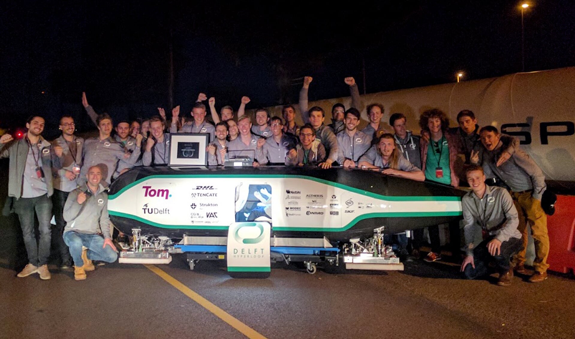 Blijdschap bij het Delftse team, hier poserend bij hun razend snelle Hyperloop. 