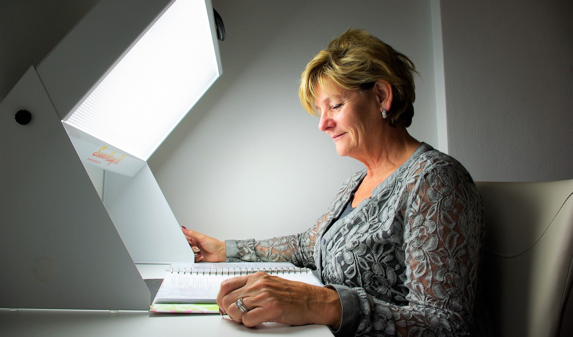 Jeannette van der Ploeg demonstreert hoe lichttherapie werkt: gewoon even voor een lamp zitten en een boekje lezen.
