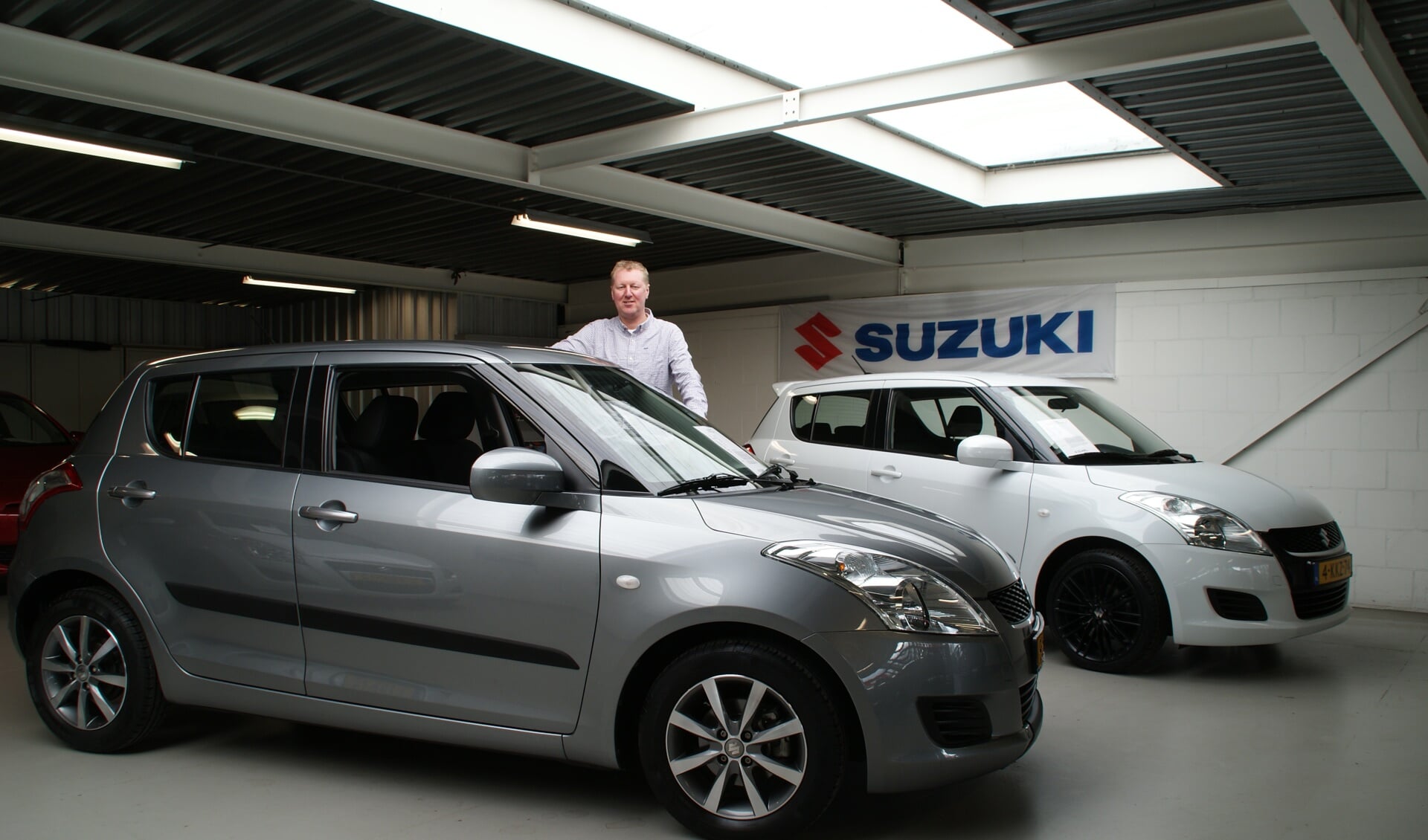 Patrick van den Berg bij de zilvergrijs kleurige Suzuki Swift 1.2 Automaat.