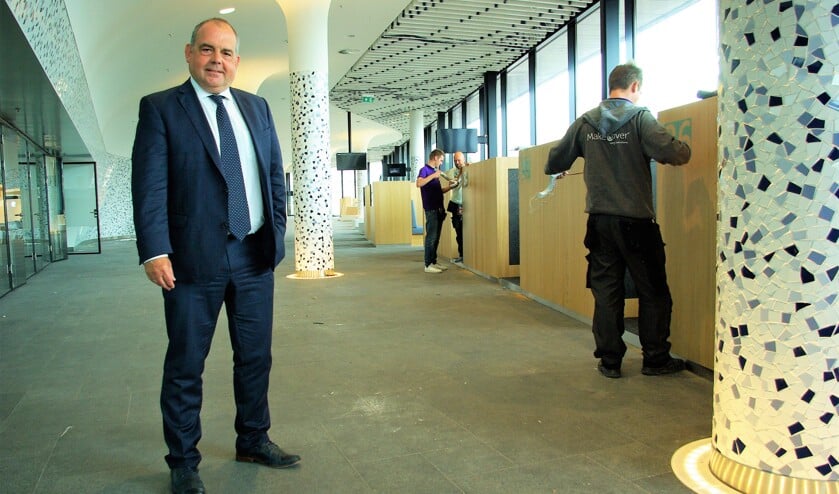 Wethouder Harpe is dinsdag in publiekshal nog in goed gezelschap van talloze bouwvakkers. Vanaf maandag kunnen Delftenaren hier terecht voor alle gemeentelijke dienstverlening. (foto: Jesper Neeleman)