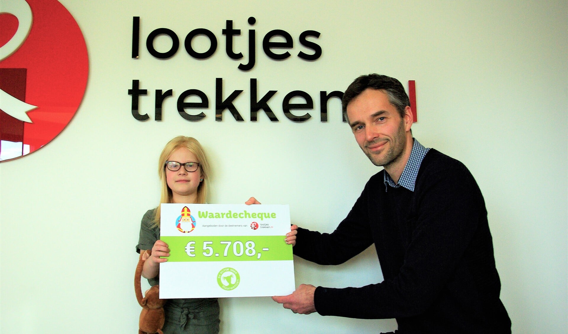 Arjan Kuiper van Lootjestrekken.nl overhandigt de cheque aan Carice en haar knuffel 'aap'. 