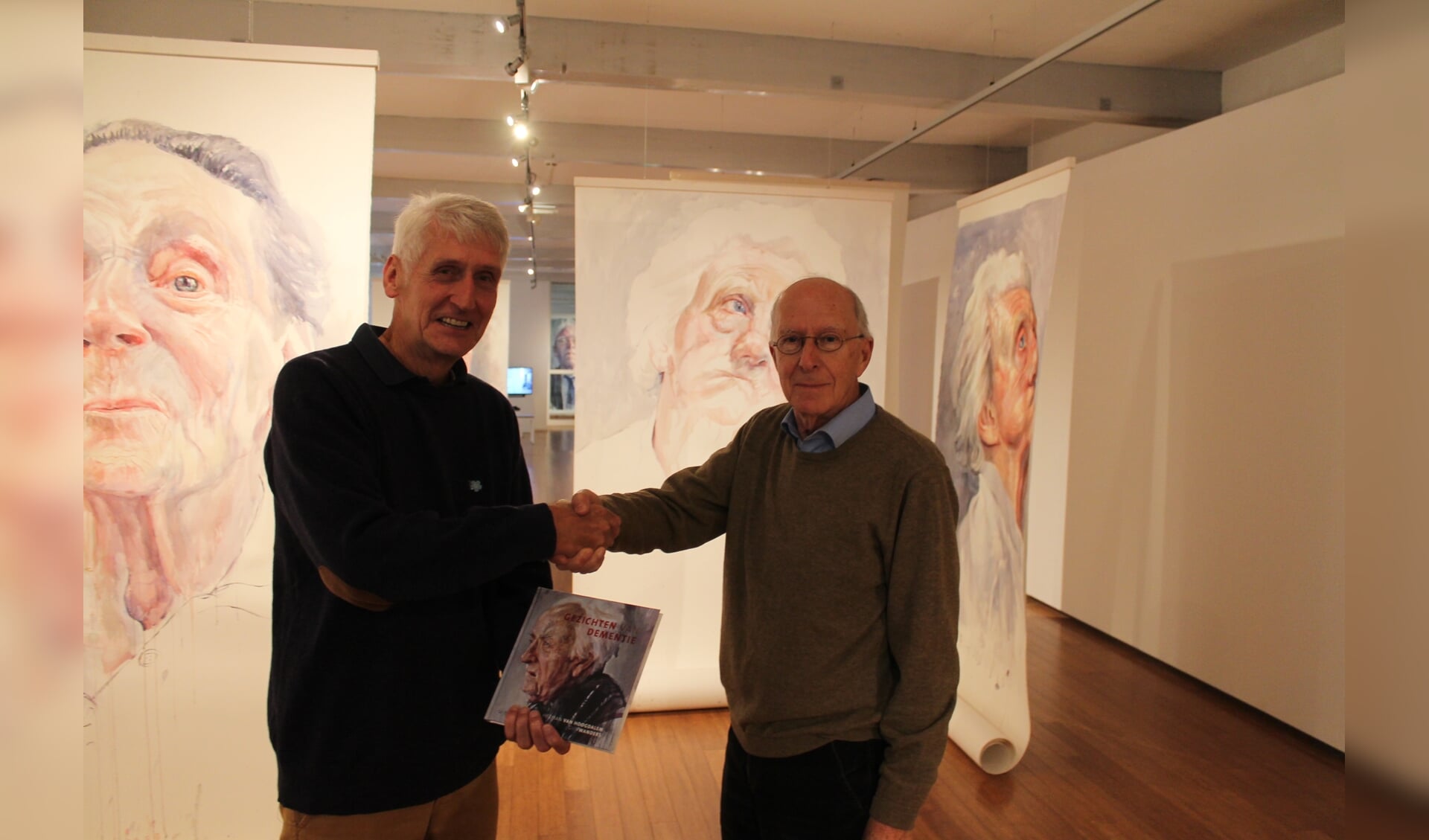 De voorzitter van Alzheimer DWO, Bert van der Lende, overhandigt het expositieboek aan de heer Wesselman