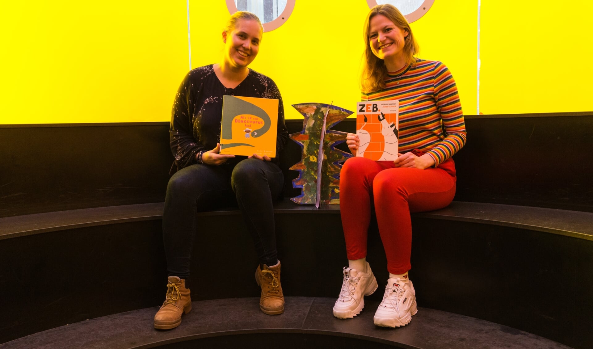 Eva en Femke van DOK Bibliotheek Delft prijzen enthousiast een kinderboek aan.