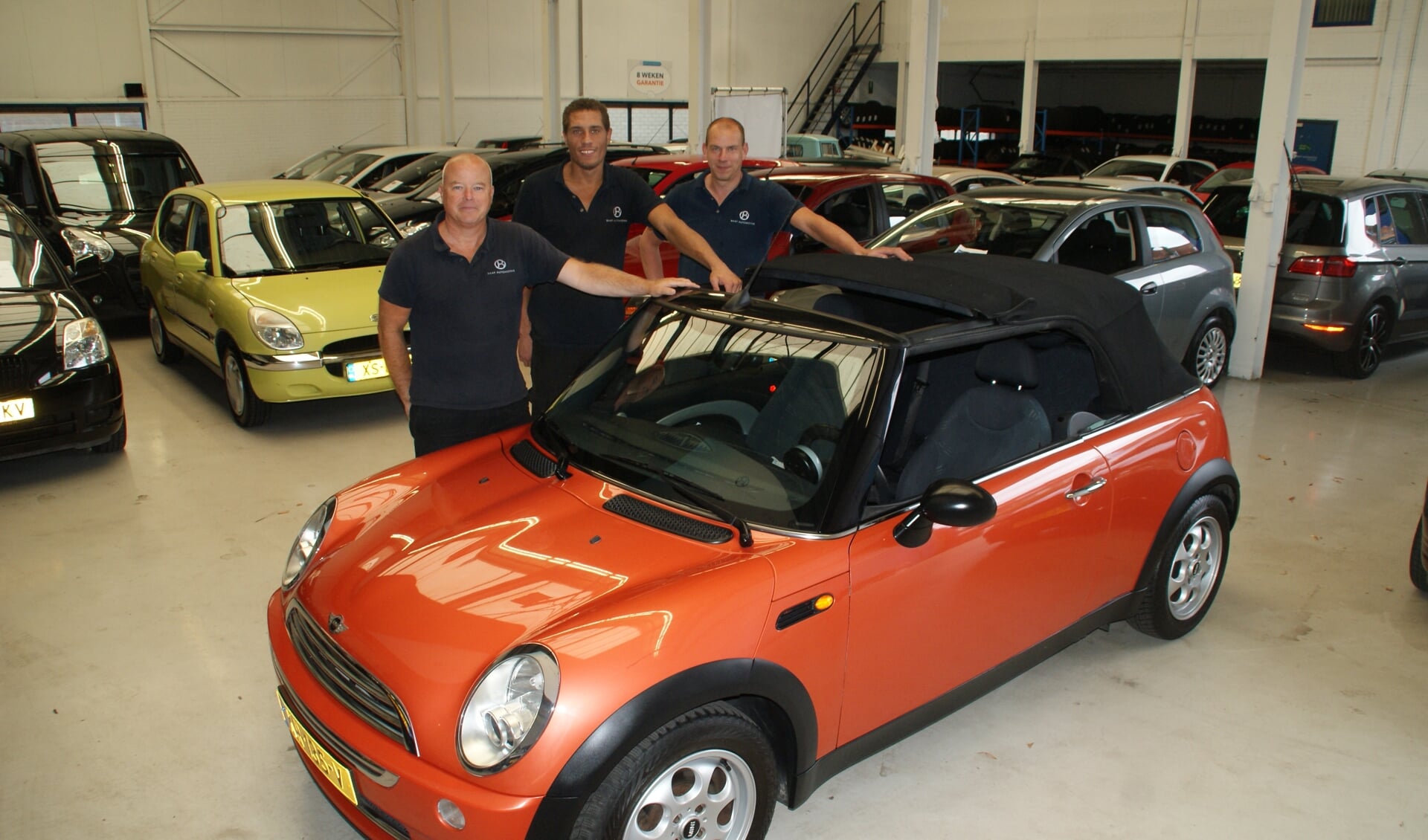 Bavelaar (links) en twee van zijn medewerkers koesteren een Mini in de showroom van Baaf Automotive.