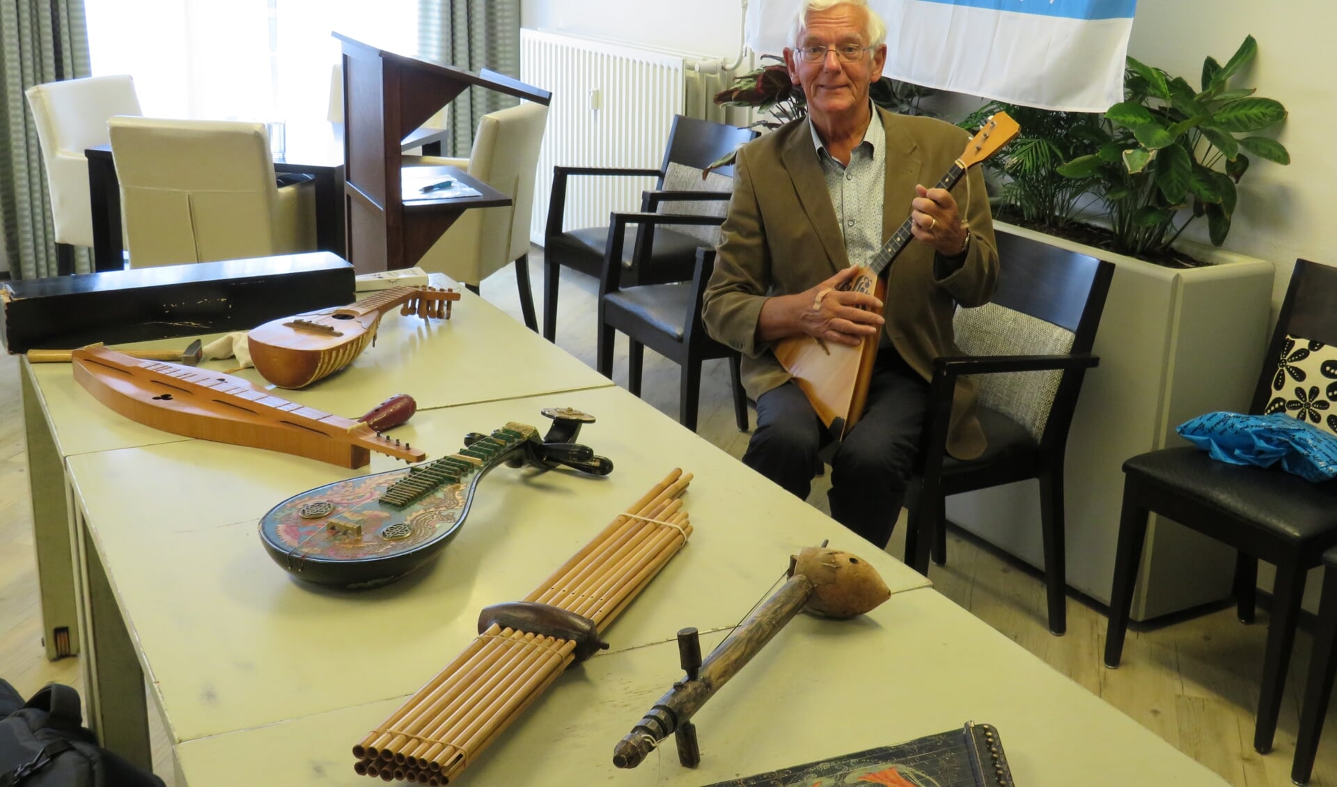 Hans Blokland, met slechts een klein deel van zijn grote verzameling muziekinstrumenten. In zijn handen de Russische balalaika. 