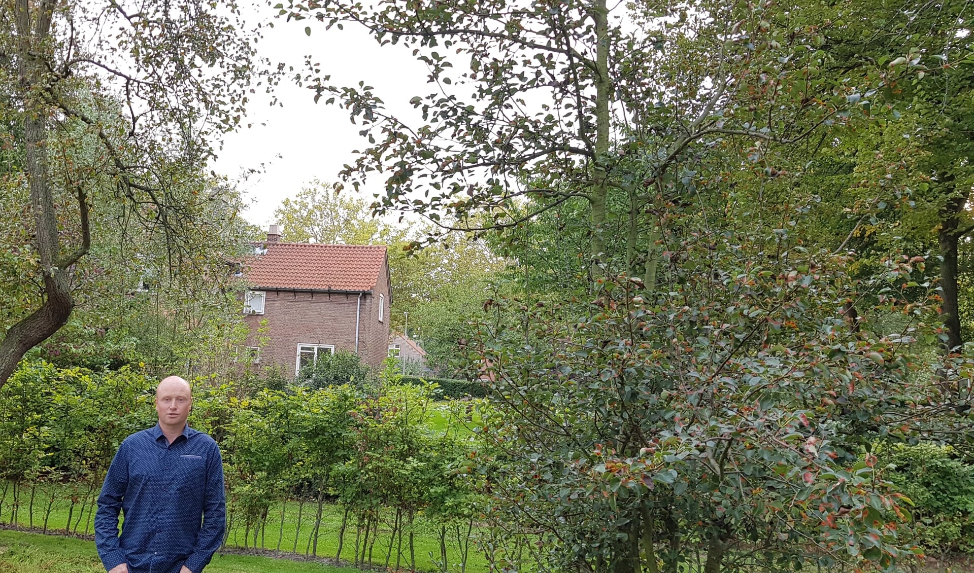 Eduard in het groen van 'zijn' fruittuinen met op de achtergrond de portierswoning
