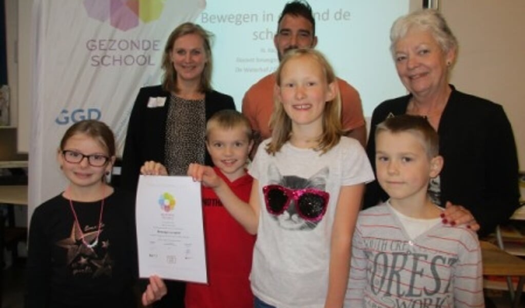 Kinderen van De Waterhof tonen het certificaat. Achter links wethouder Hatte van der Woude, rechtsboven Wilma van der Leeden