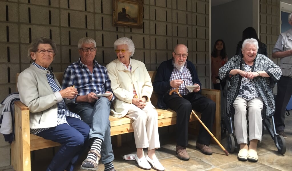 Enkele oudere buurtbewoners testen de aan hen gedoneerde ontmoetingsbank aan de Kristalweg
