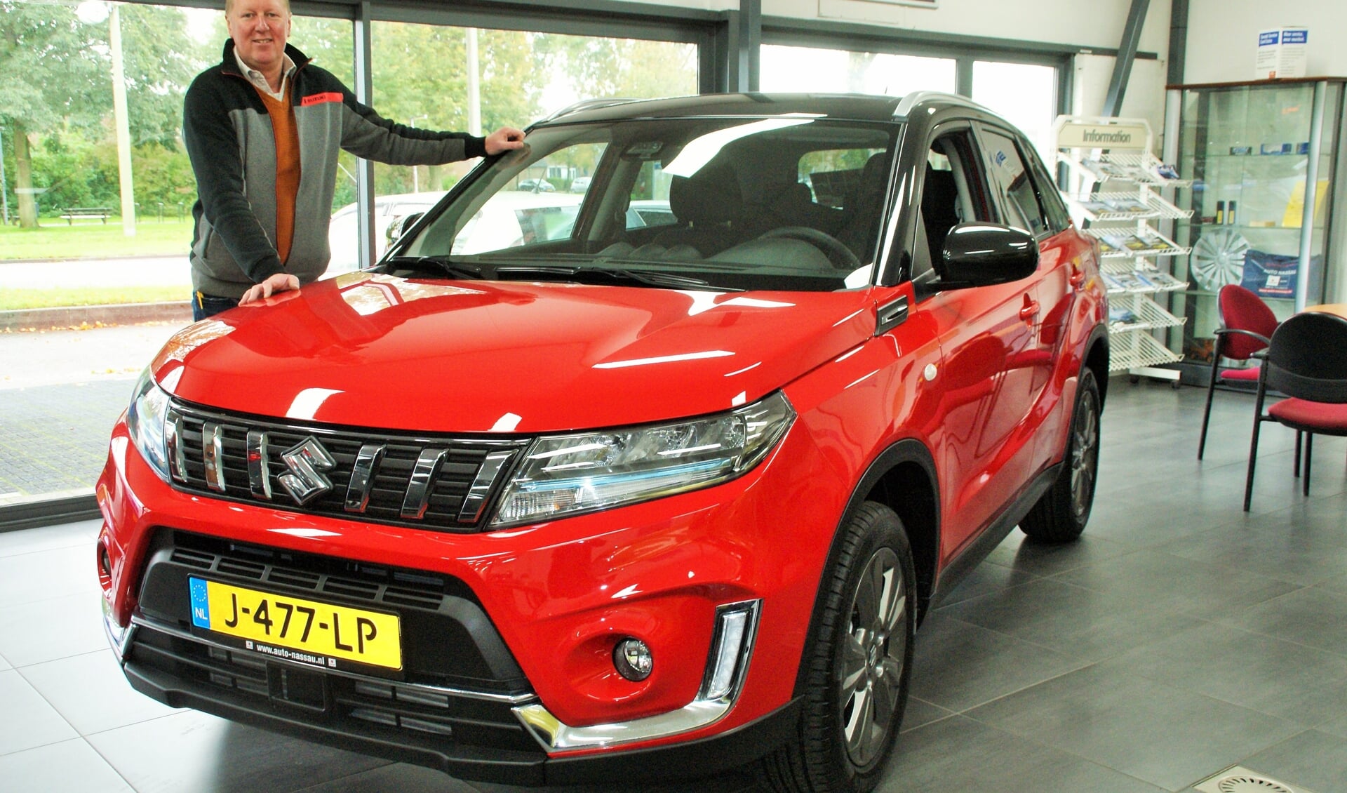 Patrick van den Berg bij de Suzuki Vitara 1.4 Hybrid, opvallend in het rood, in de showroom aan de Lagosweg. (foto: ML)