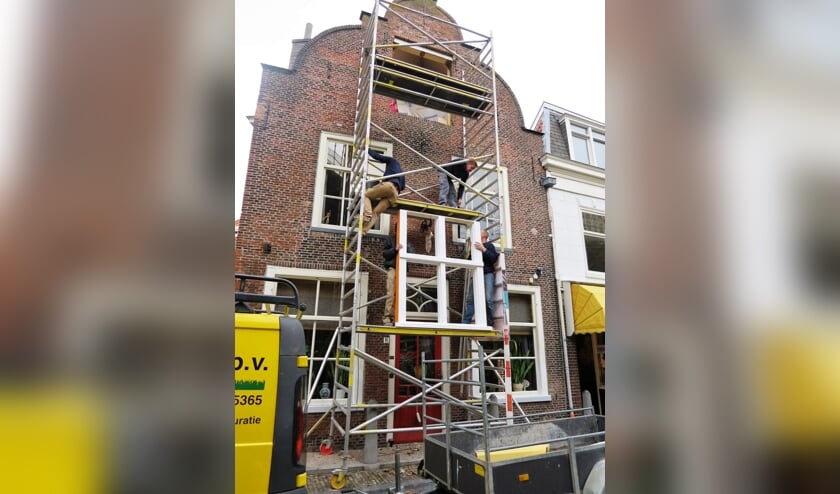 <p>Gebroeders Mensert aan het werk op de steiger in de Delftse binnenstad.</p>