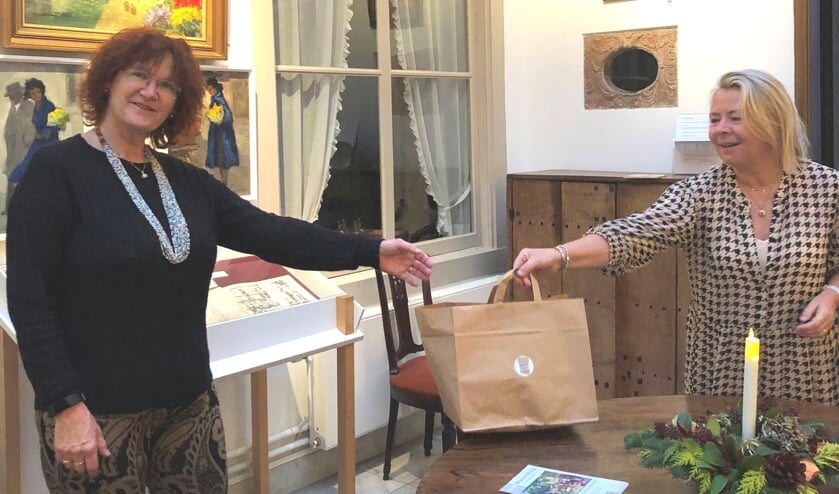 Carin Kraal – van der Leeuw (rechts) overhandigt de kerstgoodiebag aan vrijwilligster Rieneke de Pater in Museum Paul Tetar van Elven