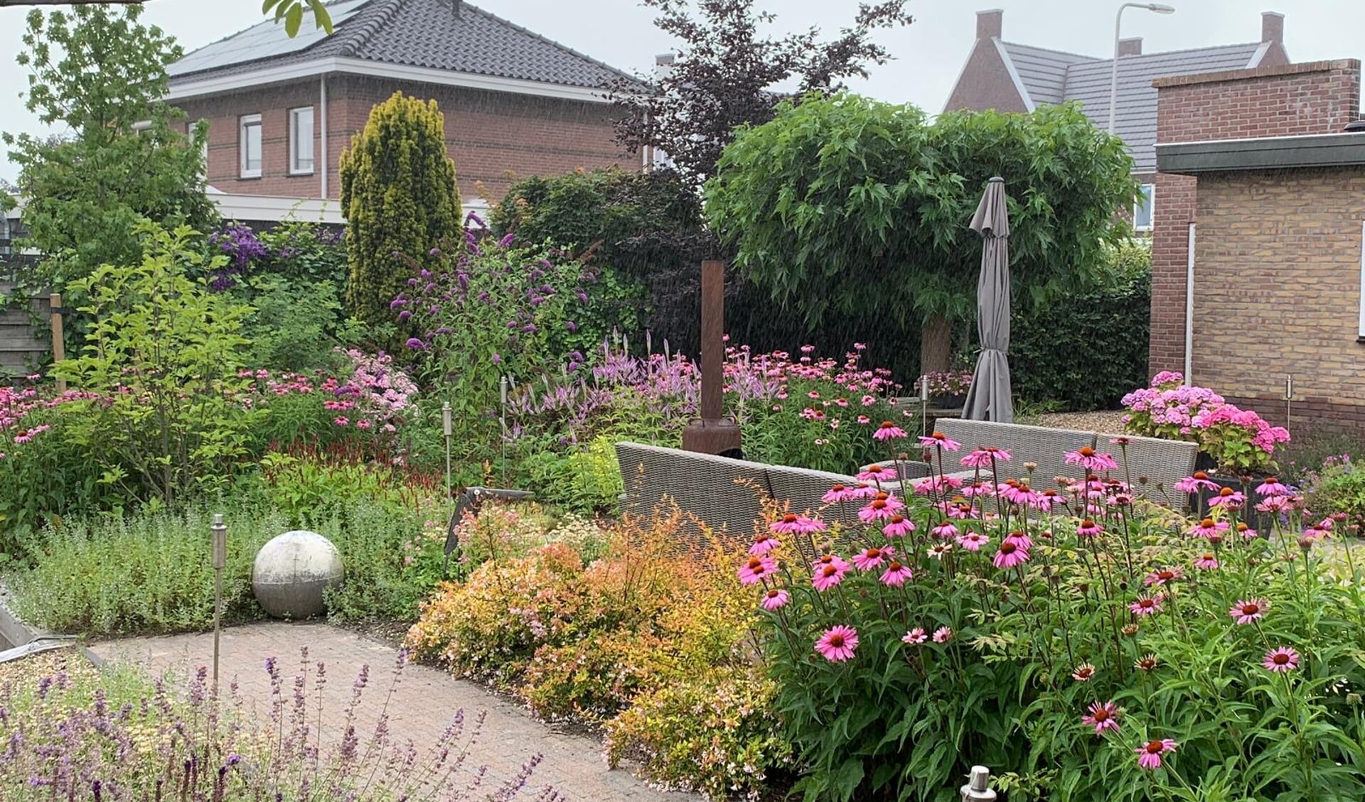Een tuin met veel beplanting en bloemen, ontworpen door
Diemel Groenvoorzieningen.