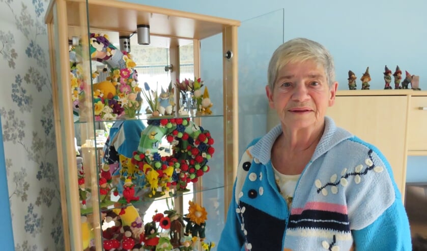 <p>Gerda van Bergen voor haar vitrinekast met haak- breiwerkjes. Ook haar trui is zelf gehaakt.</p>  