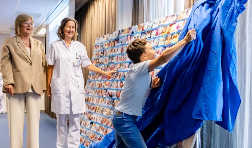 Finn (10) onthult samen met gynaecoloog Katja de Graaff (m) en obstetrieverpleegkundige Helma van Leeuwen een wandpaneel met geboortefoto&rsquo;s   
