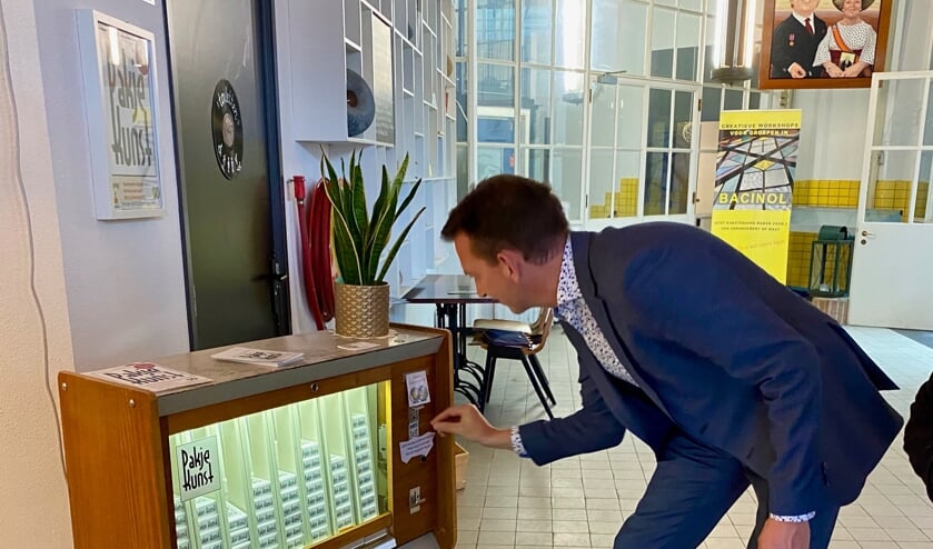 <p>Wethouder Frank van Vliet trekt een pakje kunst.</p>