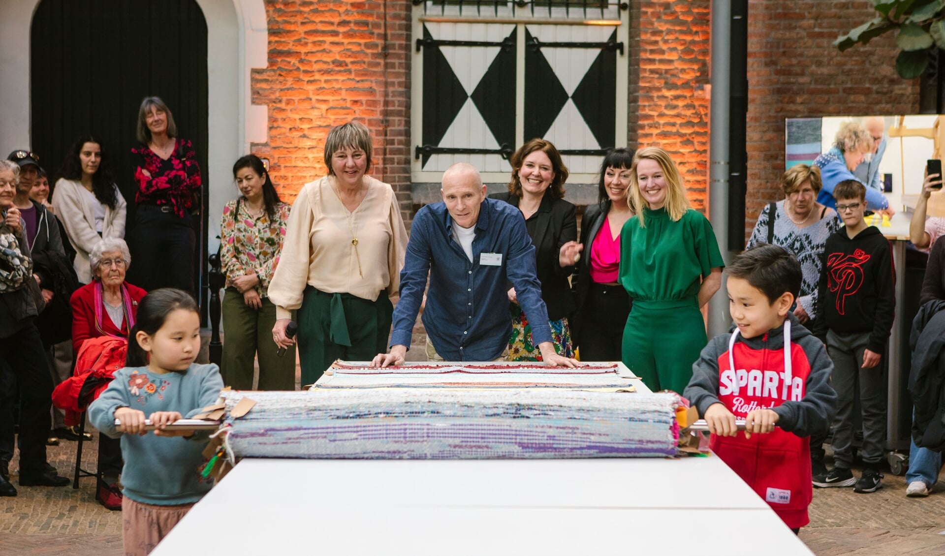 Het Kleed van Delft werd onthuld door Alina en Khalid, die ook meeweefden (Foto: Esther de Cuijper)