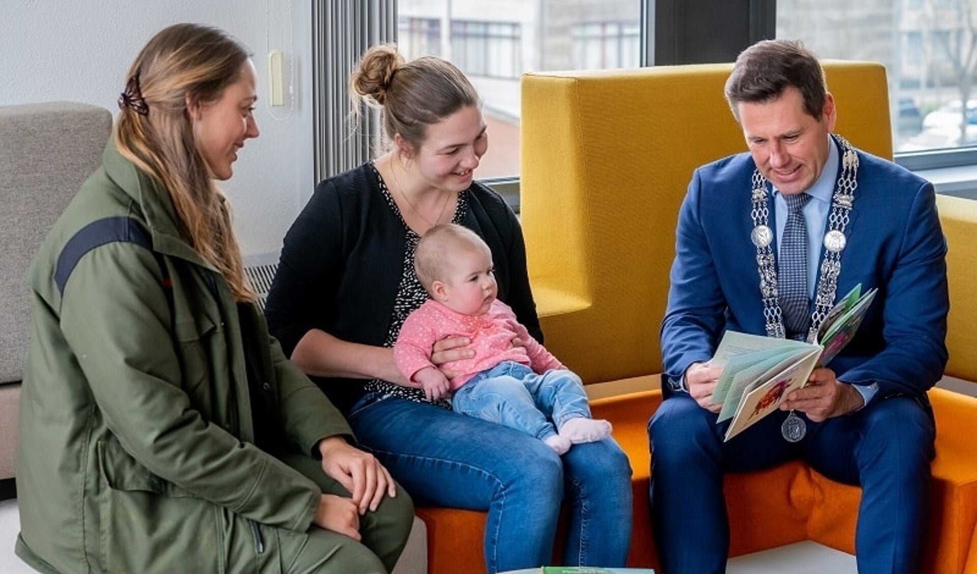 Baby Emma zit, op schoot bij haar moeder Ilse, aandachtig te luisteren naar burgemeester Björn Lugthart. Boswachter Lisa Wassenaar luistert ook mee.