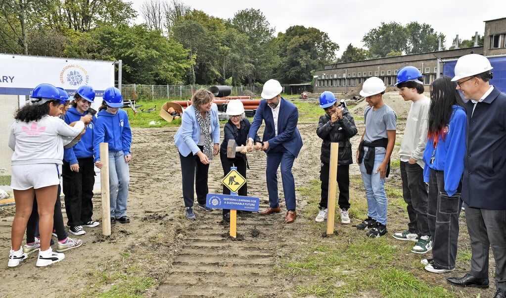 V.l.n.r. schooldirecteur Minke Veeneklaas, wethouder Karin Schrederhof en bestuursvoorzitter Ewald van Vliet slaan de eerste paal. (Foto: Erwin Dijkgraaf)