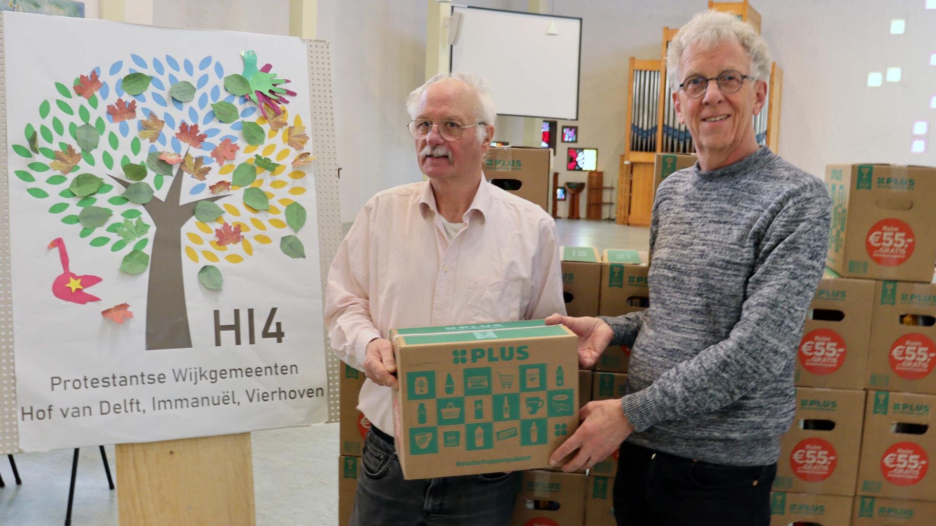 Cees van der Sluys (l), overhandigt de boodschappenpakketten aan Paul Mekking van de Voedselbank
