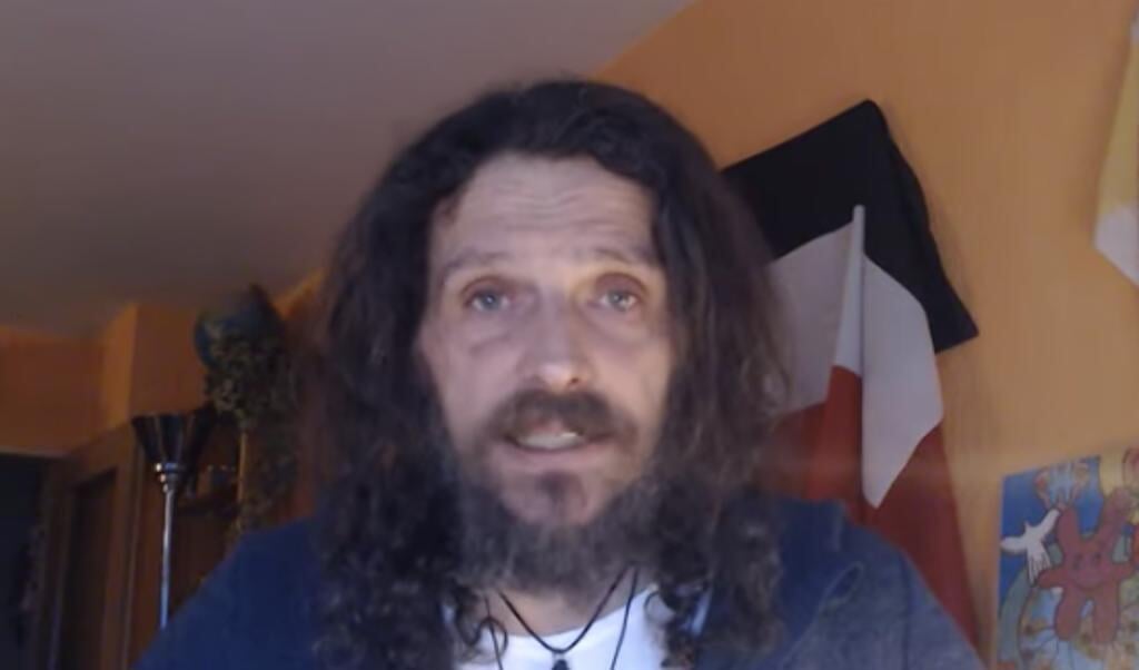 Martin Laker har en vision om et nyt Tysk Rige, hvor kvinder skal gøre, hvad mænd forlanger. I baggrunden ses det gamle tyske rigsflag. (Screenshot)