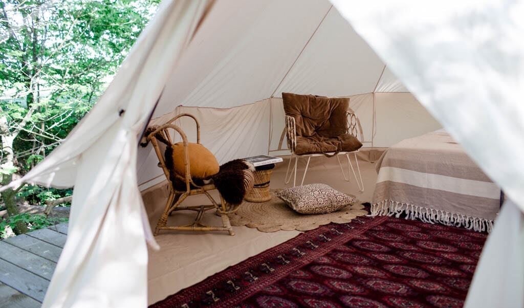 Det ægte tæppe på gulvet og den lune stemning leder tankerne lidt over mod safari, når man kigger ind i skovteltet. Dette befinder sig på Bornholm på Rø Jordbrug. ( GoGlamping)