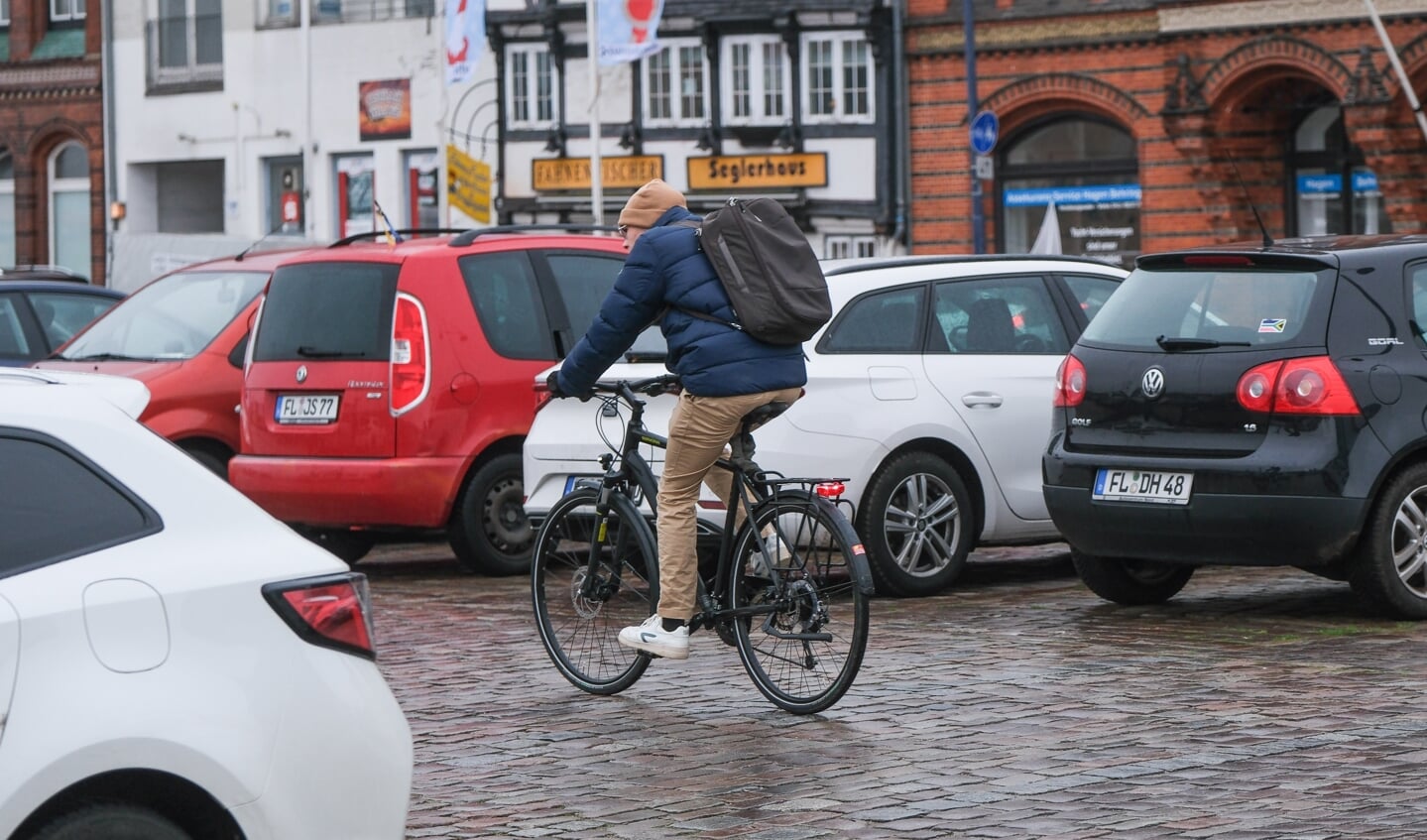 manden cykler imellem rækken af bilerne på den store parkeringsplads ved Skibbroen på havnen. meget snart skal omkring halvdelen af bilerne vige for at give plads til en cykelsti. Foto: