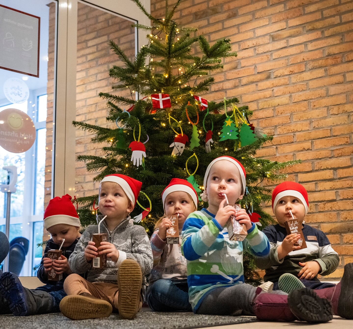 De fem børn satte sig pænt ned på rumpen og nød deres belønning for det fint pyntede træ.