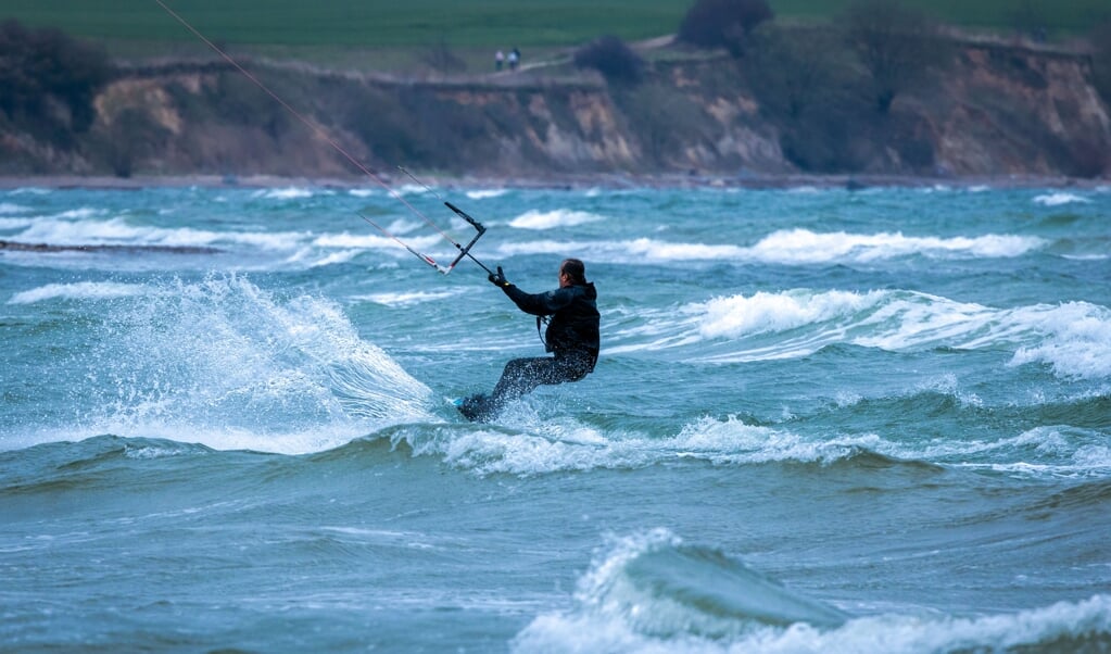 Ein Kitesurfer ist bei stürmischer See vor der Küste unterwegs.    (Jens Büttner/dpa)