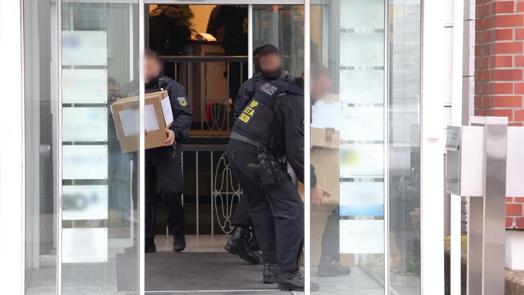 Politibetjente bærer beslaglagt materiale i kasser ud af en bygning i Solingen. Foto: